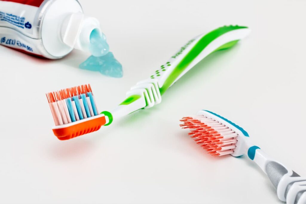 Una pasta de dientes de la que sale dentífrico y dos cepillos de dientes